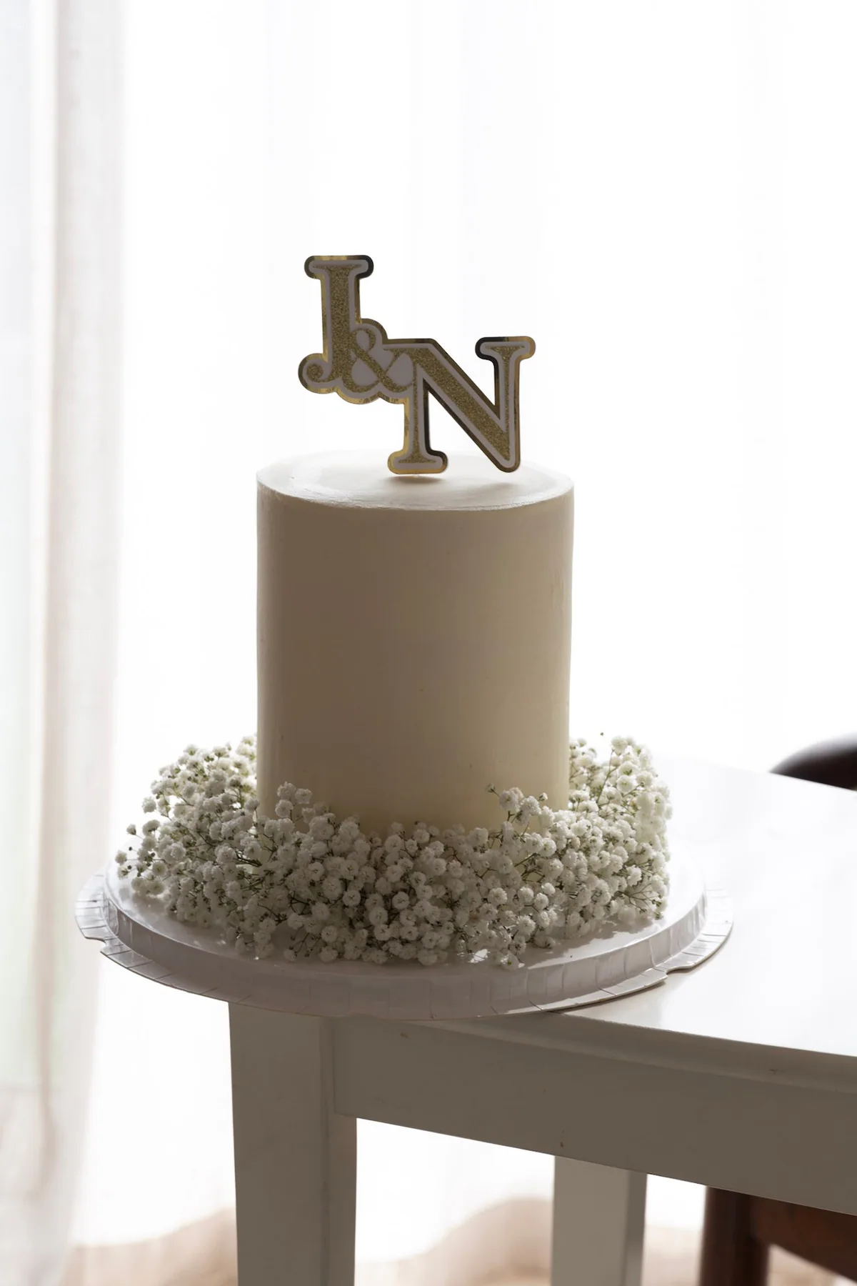 Minimal ivory cake with metallic initials and baby's breath