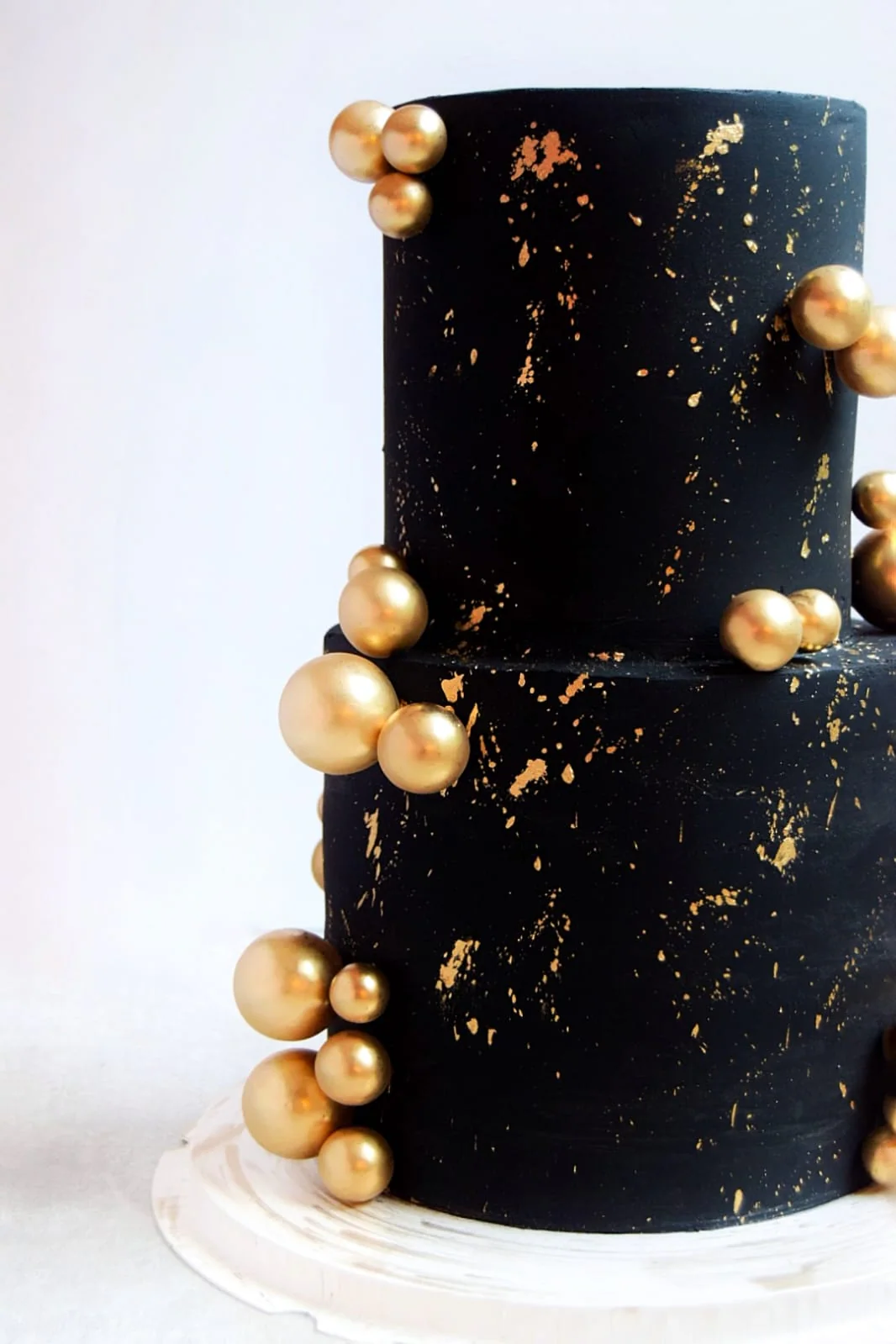 Sculptural black two-tier cake with floating gold spheres