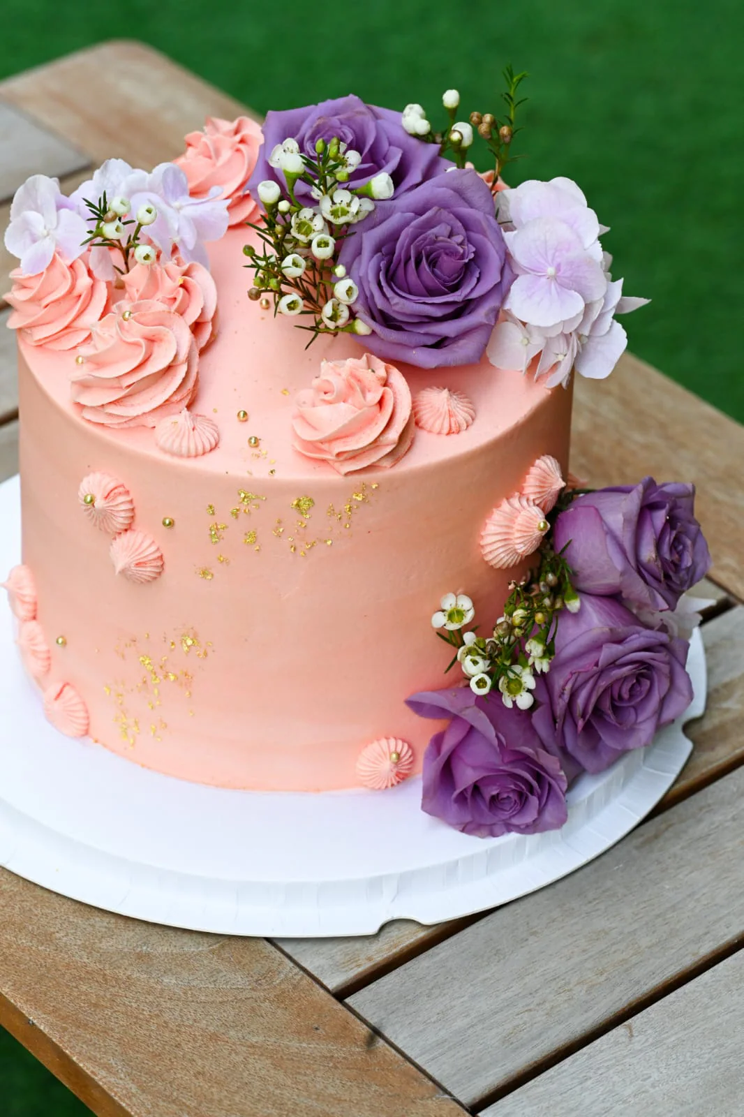 Pink floral cake with purple roses and gold leaf