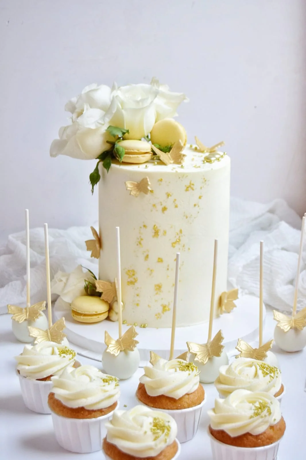 Ivory and gold cake surrounded by matching cupcakes